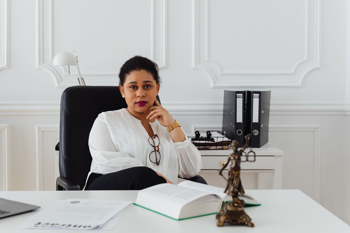 Professional portrait of a lawyer sitting at a large wooden desk with a laptop